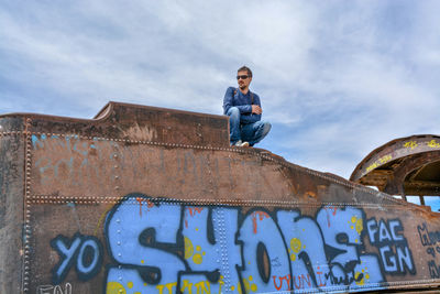 Low angle view of man on wall against sky