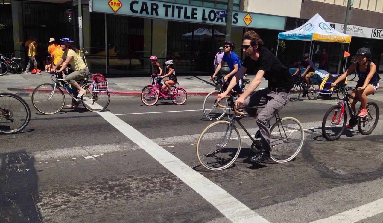 bicycle, transportation, mode of transport, land vehicle, men, street, lifestyles, city, city life, person, riding, leisure activity, large group of people, text, building exterior, walking, built structure, architecture, road