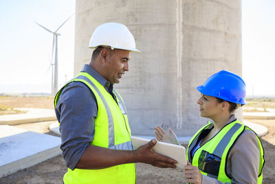 Two engineers with tablet discussing on a wind farm