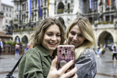 Close-up of young woman taking selfie with female friend in city