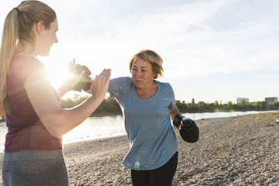 Grandmother doing boxing training with her graddaughter at the river