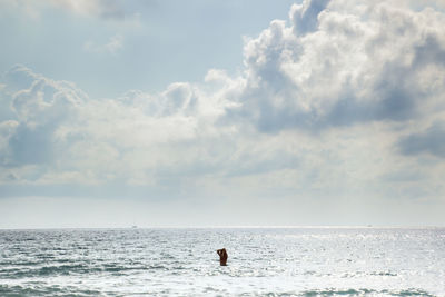 People in sea against sky