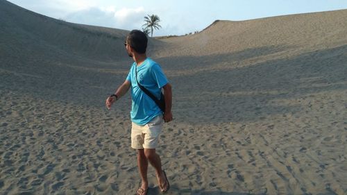 Full length rear view of man walking on beach