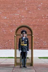 Portrait of man standing against brick wall