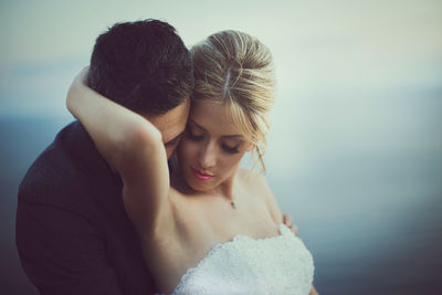 Midsection of couple kissing against sea