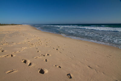 Scenic view of beach against clear blue sky