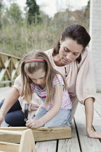 Mother and daughter nailing wooden planks on patio