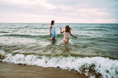 Girls playing fully dressed in lake michigan on summer day