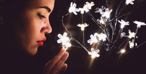 Close-up of women touching illuminated string lights