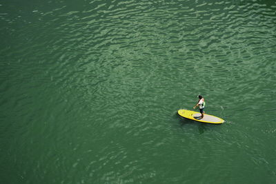 High angle view of man standing on surfboard in sea