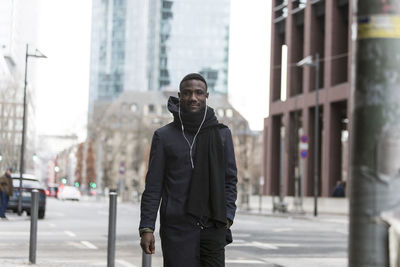 Portrait of young man standing on street in city