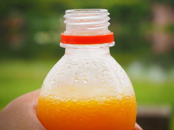 Close-up of hand holding orange bottle