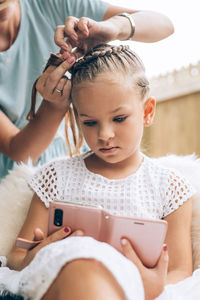 Midsection of woman hairstyling daughter