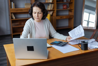 Portrait of woman using laptop while sitting on table