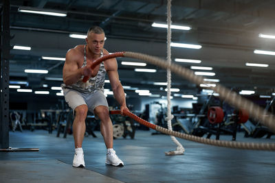 Full length of man exercising with rope at gym