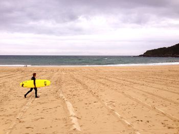 Woman standing on beach against sky