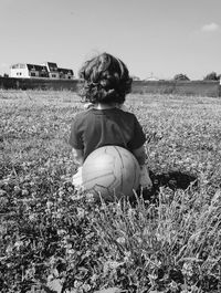 Rear view of boy playing on field against clear sky