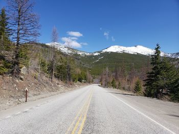 Road amidst trees and mountains against sky