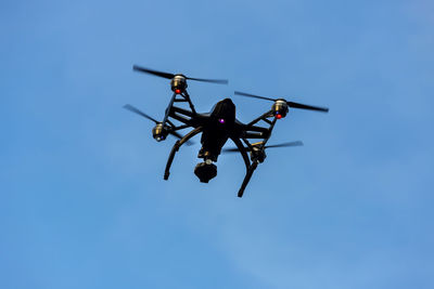 Low angle view of helicopter against clear blue sky