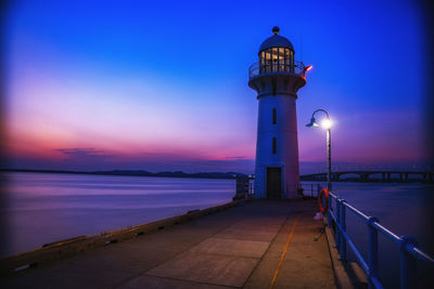 Lighthouse by sea against sky at night