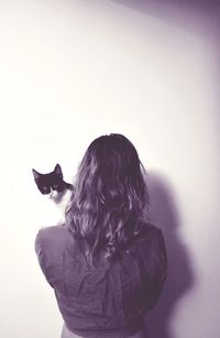 Rear view of woman with dog sitting against white background