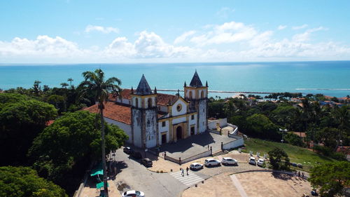 Buildings by sea against sky