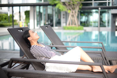 Young woman relaxing on lounge chair at poolside