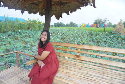 Portrait of smiling young woman standing against plants