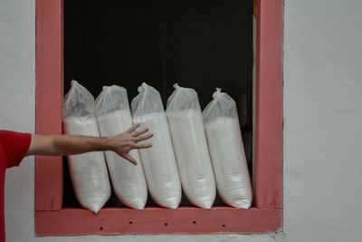 Cropped image of man touching cassava flour bags on window frame