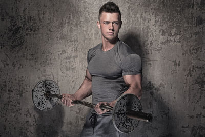 Portrait of young man standing against wall