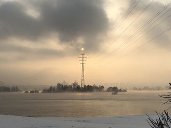 Electricity pylon on land against sky during winter