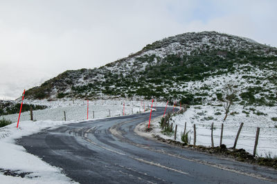 Road by mountain against sky during winter