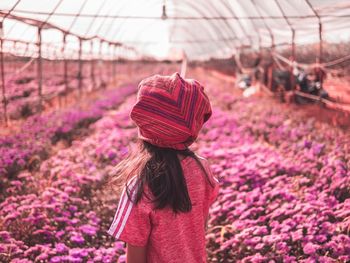 Rear view of woman standing on pink flowering plants