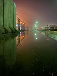 Illuminated bridge over river against sky at night