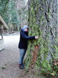 Full length of man standing on tree trunk in forest