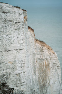 Rock formation by sea against sky