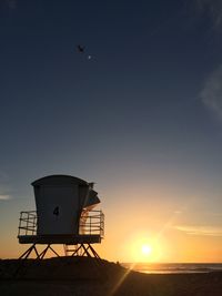 Low angle view of lifeguard hut against sky at sunset