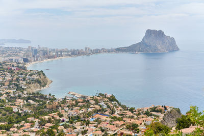 Aerial view of townscape by sea against sky