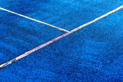 White lines on the edge of a blue tennis court 