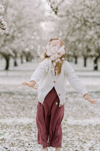 Young girl throwing petals at camera in an almond orchard