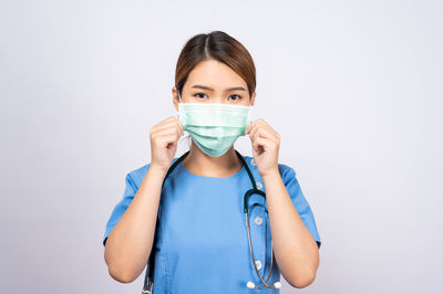 Portrait of woman wearing mask against white background