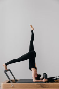 Low section of woman doing yoga against white background
