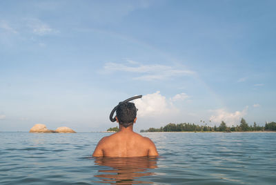 Rear view of man with snorkel in sea