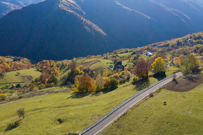 Aerial view of epic countryside road and autumn forest from above, drone point of view