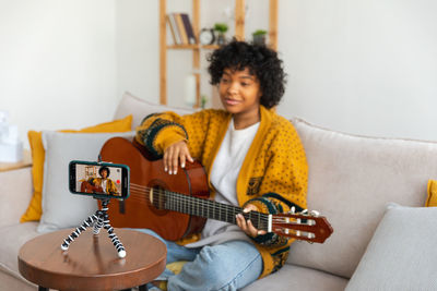 Portrait of young woman playing guitar at home