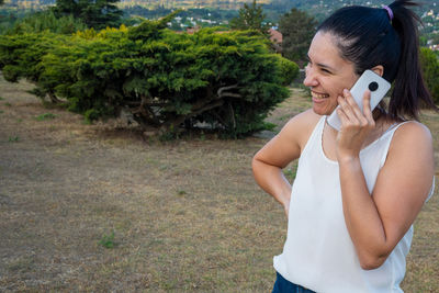 Young woman using mobile phone while standing on grassy field