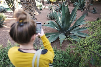 Rear view of woman photographing plants