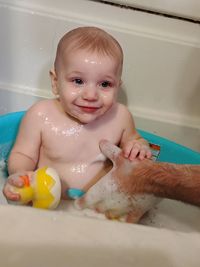 Smiling baby boy having a bath in tub at home