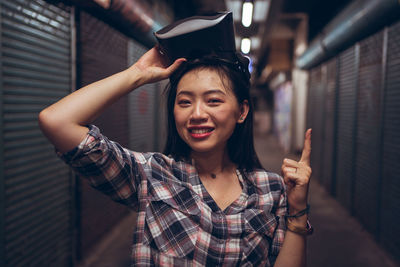 Portrait of smiling young woman standing against wall