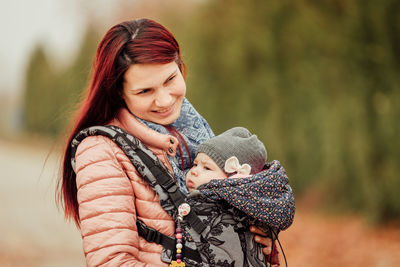 Smiling mother with daughter outdoors during winter